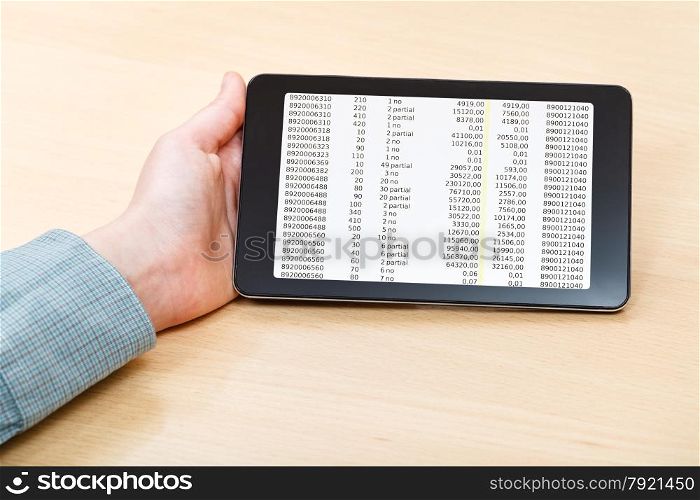 businessman hand with tablet PC with financial data on screen at office table