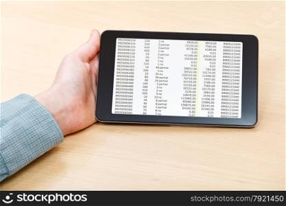 businessman hand with tablet PC with financial data on screen at office table