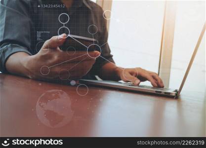 businessman hand working and smart phone and laptop with social media diagram on wooden desk in office