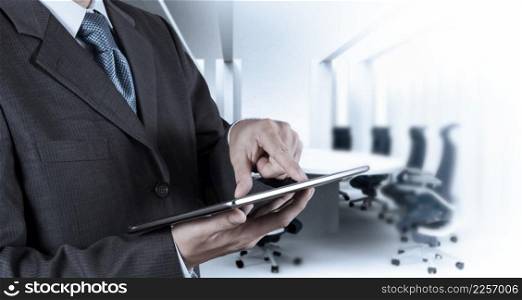 Businessman hand working with a digital tablet on meeting room background