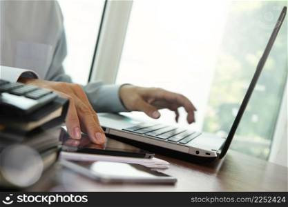 businessman hand working with digital tablet and laptop on wooden desk in office