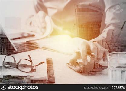 businessman hand working with finances about cost and calculator and latop with mobile phone on withe desk in modern office with buildings exposure