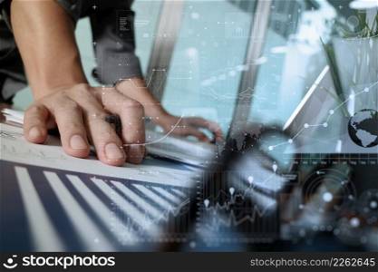 businessman hand working with new modern computer and business strategy documents and difital layers diagram with green plant and eye glasses foreground on wooden desk in office
