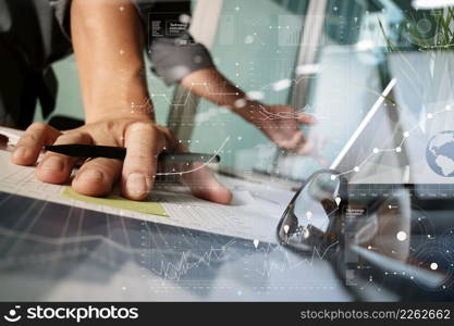 businessman hand working with new modern computer and business strategy documents and difital layers diagram with green plant and eye glasses foreground on wooden desk in office