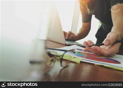 businessman hand working with new modern computer and business strategy documents digital layer with eyeglass and glass of water foreground on wooden desk in office