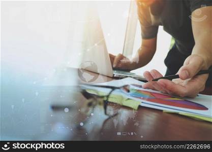 businessman hand working with new modern computer and business strategy documents digital layer with eyeglass and glass of water foreground on wooden desk in office