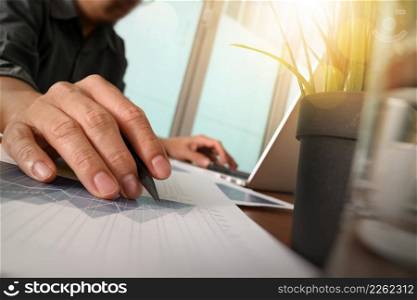 businessman hand working with new modern computer and business strategy documents with green plant and glass of water foreground on wooden desk in office