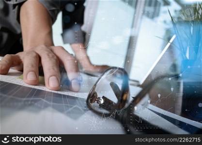 businessman hand working with new modern computer and business strategy documents with green pant and eye glasses foreground on wooden desk in office