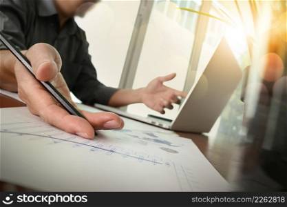 businessman hand working with new modern computer and business strategy documents with green plant and glass of water foreground on wooden desk in office