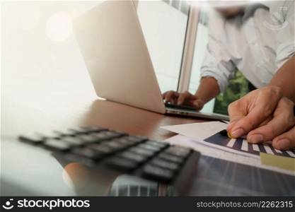 businessman hand working with new modern computer laptop and business strategy on wooden desk with calculator and eye glasses foreground as concept