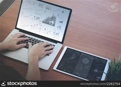businessman hand working with new modern computer laptop and pro digital tablet with digital business diagram on wooden desk as concept