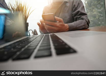businessman hand working with new modern computer with smartphone on wooden desk in office
