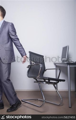 Businessman handcuffed to his office chair, walking away