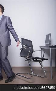 Businessman handcuffed to his office chair, walking away