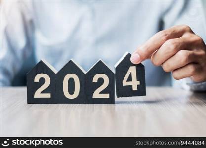 Businessman hands holding 2024 Happy New Year with house model on table office. New House, Financial, Property insurance, real estate, savings and New Year Resolution concepts