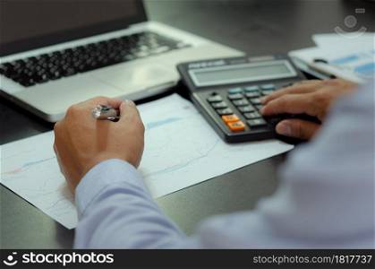 businessman hands holding pens and business documents at desk and calculator. Business, finance, tax and investment concept.