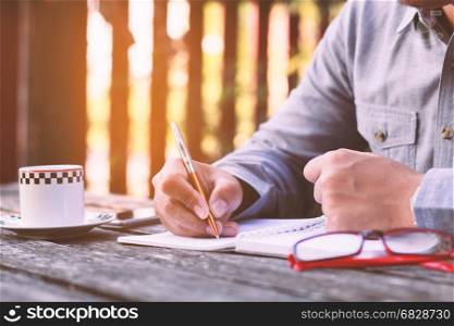 Businessman Hands writting with coffee and glasses.