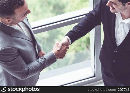 Businessman handshake with another businessman partner in modern workplace office. People corporate business deals concept.. Businessmen handshake business deal in office.