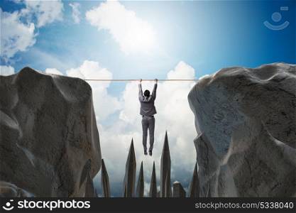 Businessman hanging on rope in danger concept