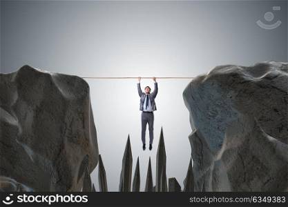 Businessman hanging on rope in danger concept