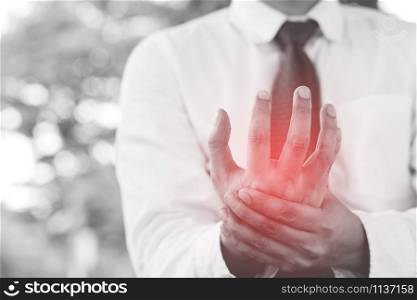 businessman having Injury wrist pain in hands while work outdoor symptomatic office syndrome. health care concept. black and white. Focus red body on to show pain.