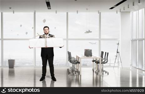 Businessman hold gift box. Young businessman in office with boxes of gifts in hands