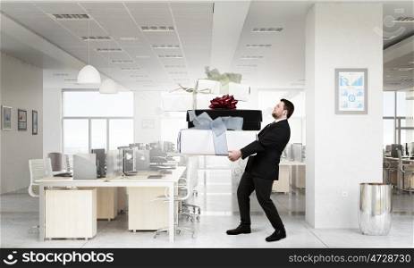 Businessman hold gift box. Young businessman in office with boxes of gifts in hands