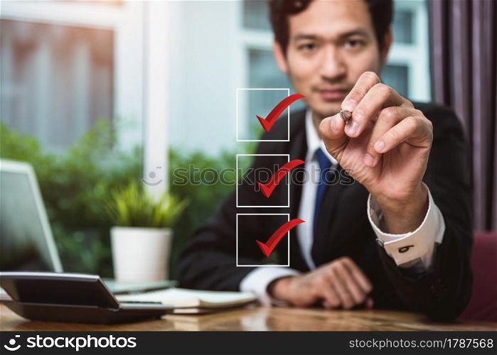 Businessman hold pen tick check boxes at him office