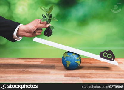 Businessman hold seedling or young tree on scale against CO2 icon, promote forest regeneration by corporate ecology responsibility as sustainable solution to reduce CO2 emission for environment. Alter. Businessman hold seedling or young tree on scale against CO2 icon. Alter