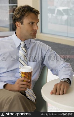 Businessman holding a coffee cup and thinking