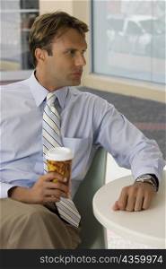 Businessman holding a coffee cup and thinking