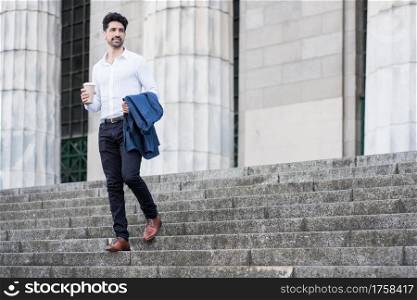 Businessman holding a cup of coffee on way to work outdoors. Business concept.