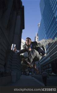 Businessman holding a disposable cup running in mid-air