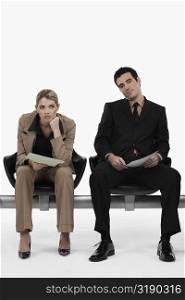 Businessman holding a file with a businesswoman sitting beside him and looking serious