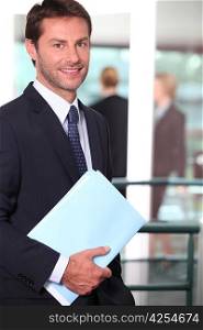 Businessman holding a file with colleagues out of focus in the background