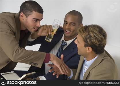 Businessman holding a glass of beer with two businessmen shaking hands