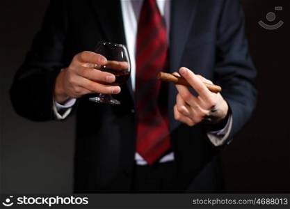 Businessman holding a glass of cognac and cigar