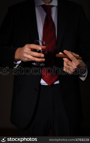 Businessman holding a glass of cognac and cigar