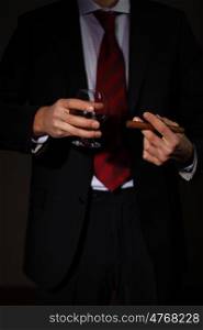 Businessman holding a glass of cognac and cigar