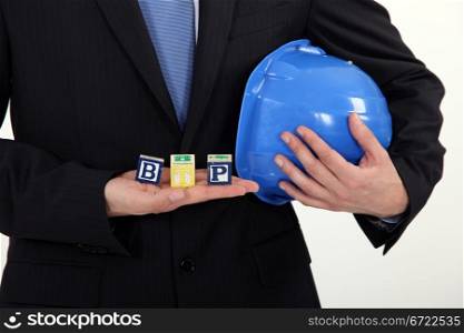 Businessman holding a hard hat and letter blocks
