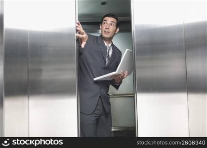 Businessman holding a laptop in an elevator