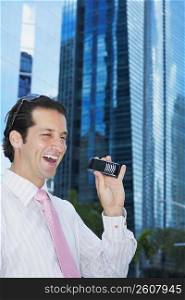 Businessman holding a mobile phone and laughing