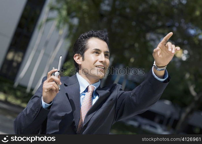 Businessman holding a mobile phone and pointing upward