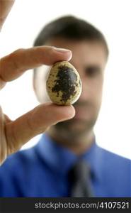 Businessman holding a quail fragile egg, selective focus
