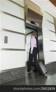 Businessman holding a suitcase and entering a lift