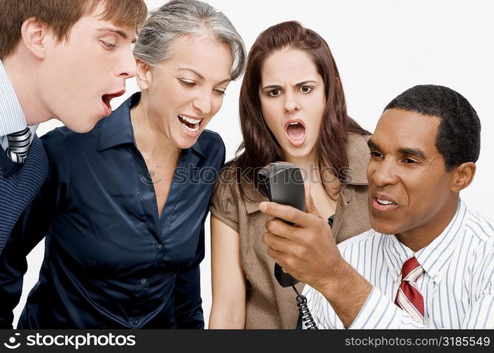 Businessman holding a telephone with three business executives shouting