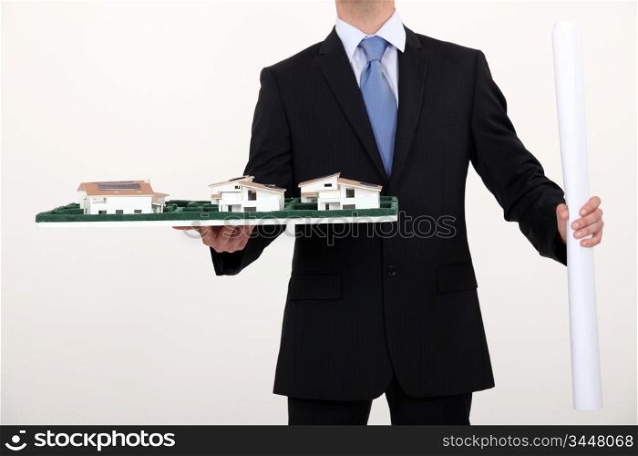 businessman holding an architectural model and a blueprint
