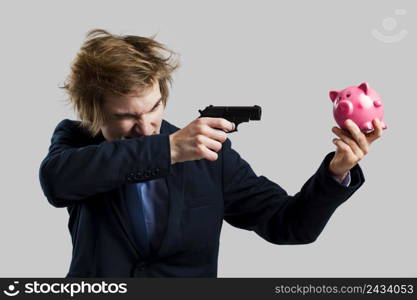 Businessman holding and pointing a gun to a piggy bank