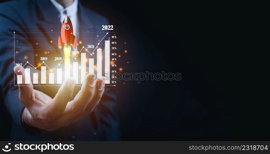 Businessman holding and showing a growing virtual hologram of statistics, graph and chart with arrow up on dark background. Stock market. Business growth, planing and strategy concept