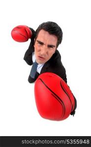 businessman holding boxing gloves looking ferocious